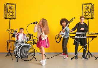 Teenage musicians with drawing instruments playing against color wall